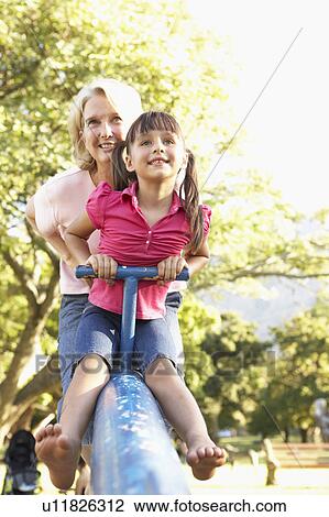 Stock Image - Grandmother And Granddaughter Riding On See Saw In Playground. Fotosearch