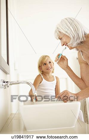 Grandmother Brushing Teeth In Bathroom With Granddaughter Watching View Large Photo Image Stock Photo - Grandmother Brushing Teeth In Bathroom With Granddaughter Watching. Fotosearch