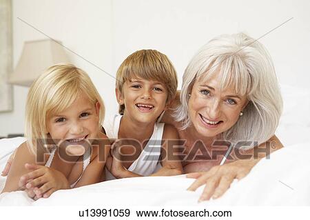 Grandmother Relaxing On Bed With Grandchildren View Large Photo Image Stock Photo - Grandmother Relaxing On Bed With Grandchildren. Fotosearch