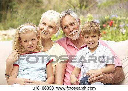 Stock Image - Grandparents And Grandchildren Relaxing In Garden. Fotosearch