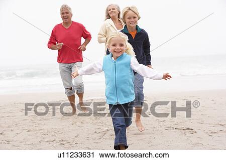 Stock Image - Grandparents And Grandchildren Running On Winter Beach Together. Fotosearch