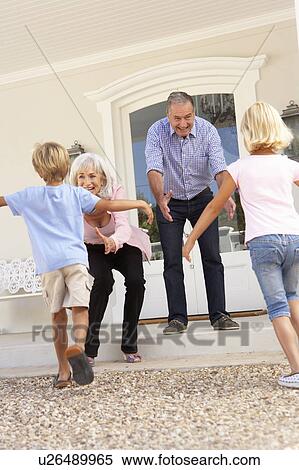 Stock Photography - Grandparents Welcoming Grandchildren On Visit To Home. Fotosearch