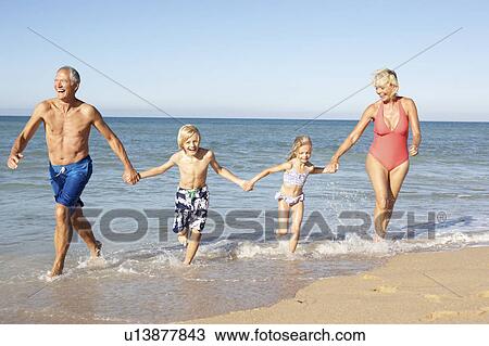 Stock Image - Grandparents With Grandchildren Enjoying Beach Holiday Together. Fotosearch