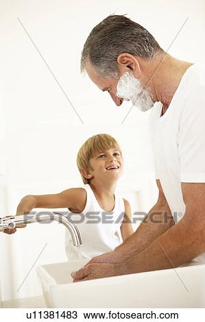 Stock Image - Grandson Watching Grandfather Shaving In Bathroom Mirror. Fotosearch