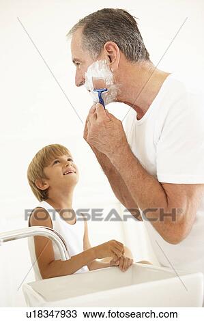 Stock Image - Grandson Watching Grandfather Shaving In Bathroom Mirror. Fotosearch