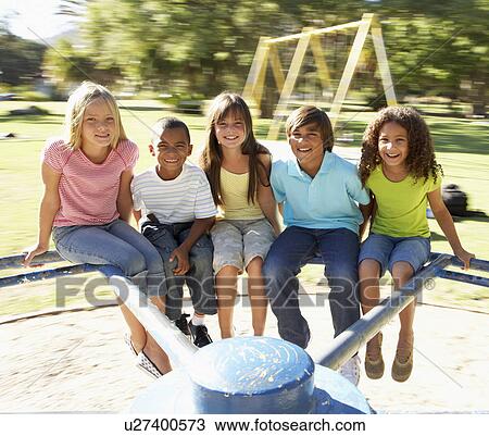 Stock Image - Group Of Children Riding On Roundabout In Playground. Fotosearch