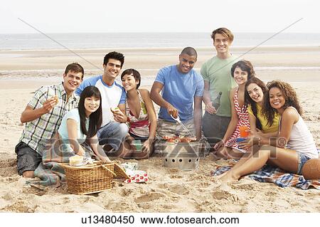 Stock Image - Group Of Friends Enjoying Barbeque On Beach Together. Fotosearch