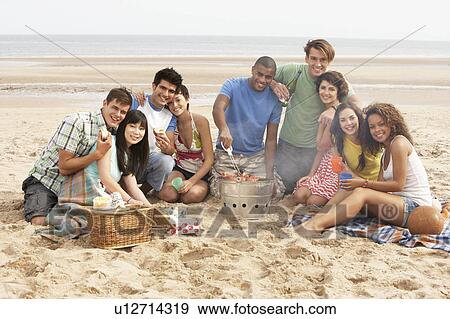 Stock Photo - Group Of Friends Enjoying Barbeque On Beach Together. Fotosearch