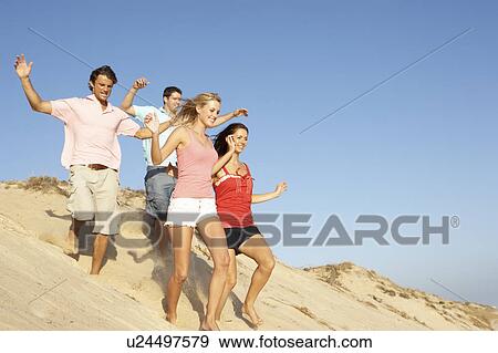 Group Of Friends Enjoying Beach Holiday Running Down Dunes View Large Photo Image Stock Photo - Group Of Friends Enjoying Beach Holiday Running Down Dunes. Fotosearch