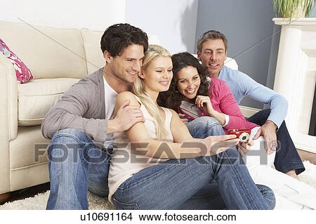 Picture - Group Of Friends Looking At Pictures On Digital Camera At Home . Fotosearch