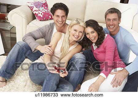Stock Image - Group Of Friends Looking At Pictures On Digital Camera At Home . Fotosearch
