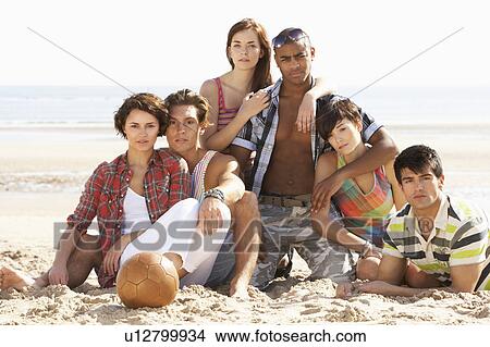 Picture - Group Of Friends Relaxing On Beach With Football Together. Fotosearch
