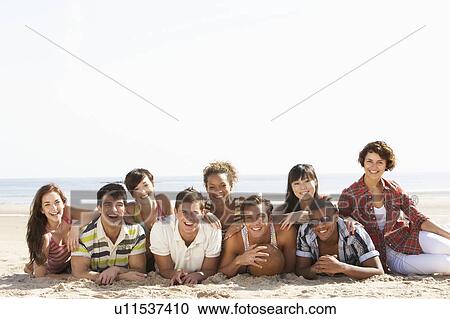 Stock Image - Group Of Friends Sitting On Beach Together. Fotosearch