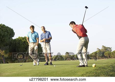 Stock Image - Group Of Male Golfers Teeing Off On Golf Course. Fotosearch