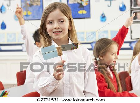 Stock Image - Group Of Primary Schoolchildren And Teacher Having lesson In Classroom. Fotosearch