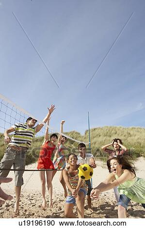 Stock Image - Group Of Teenage Friends Playing Volleyball On Beach. Fotosearch