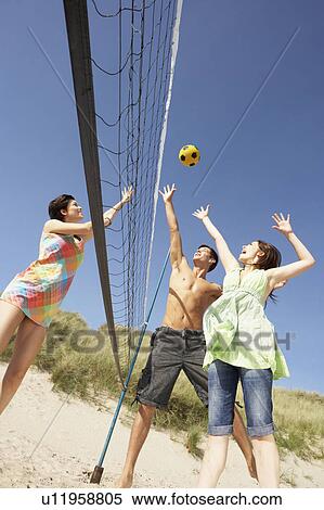 Stock Photography - Group Of Teenage Friends Playing Volleyball On Beach. Fotosearch