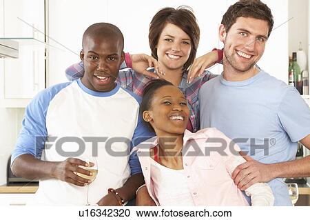Stock Image - Group Of Young Friends Enjoying Glass Of Wine In Modern Kitchen. Fotosearch