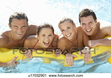 Stock Image - Group of Young friends having fun in pool. Fotosearch
