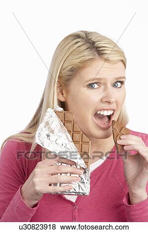 Stock Photo - Guilty Looking Young Woman Eating Big Bar Of Chocolate In Studio. Fotosearch