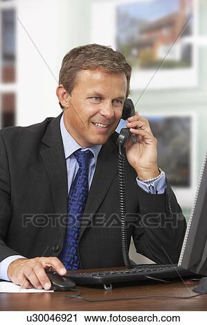 Male Estate Agent Talking On Phone At Desk View Large Photo Image Stock Image - Male Estate Agent Talking On Phone At Desk. Fotosearch