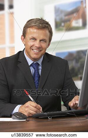 Stock Photo - Male Estate Agent Working At Desk. Fotosearch