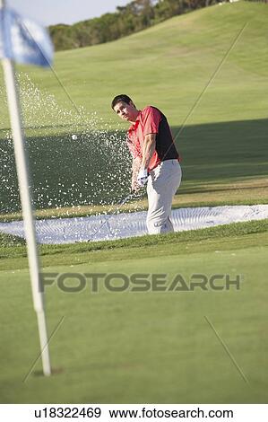Stock Photo - Male Golfer Playing Bunker Shot On Golf Course. Fotosearch