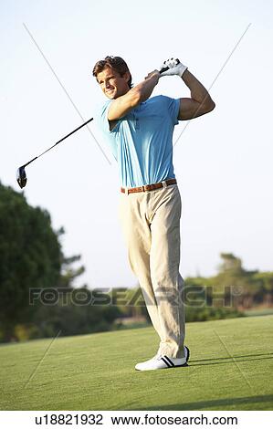 Stock Image - Male Golfer Teeing Off On Golf Course. Fotosearch