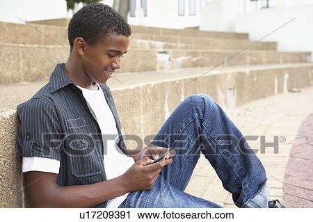 Male Teenage Student Sitting Outside On College Steps Using Mobile Phone View Large Photo Image Stock Image - Male Teenage Student Sitting Outside On College Steps Using Mobile Phone. Fotosearch