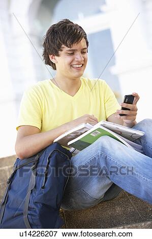 Male Teenage Student Sitting Outside On College Steps Using Mobile Phone View Large Photo Image Stock Photo - Male Teenage Student Sitting Outside On College Steps Using Mobile Phone. Fotosearch