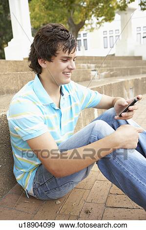 Male Teenage Student Sitting Outside On College Steps Using Mobile Phone View Large Photo Image Stock Photo - Male Teenage Student Sitting Outside On College Steps Using Mobile Phone. Fotosearch