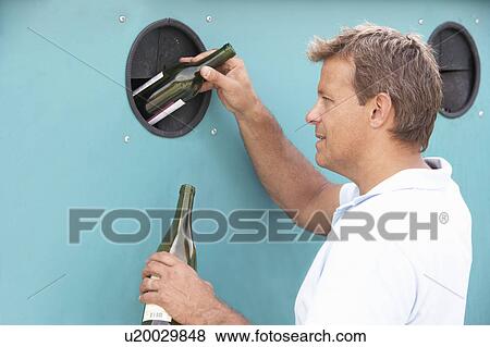 Stock Photo - Man At Recycling Centre Disposing Of Glass At Bottle Bank. Fotosearch