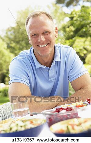 Stock Photo - Man Enjoying Meal In Garden. Fotosearch