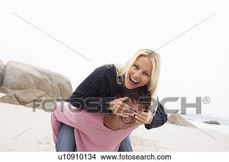 Picture - Man Giving Woman Piggyback On Winter Beach. Fotosearch