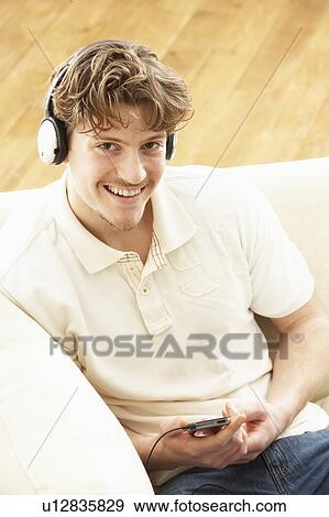 Man Listening To MP3 Player On Headphones Relaxing Laying On Rug At Home View Large Photo Image Stock Photo - Man Listening To MP3 Player On Headphones Relaxing Laying On Rug At Home . Fotosearch