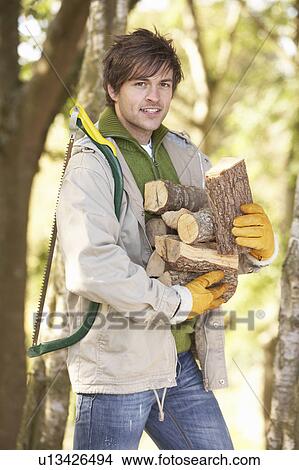 Man Outdoors In Autumn Woodland Gathering Logs View Large Photo Image Picture - Man Outdoors In Autumn Woodland Gathering Logs. Fotosearch