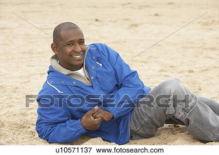 Man Relaxing On Beach In Autumn Clothing View Large Photo Image Stock Photo - Man Relaxing On Beach In Autumn Clothing. Fotosearch