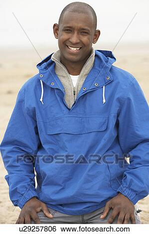 Stock Photograph - Man Relaxing On Beach In Autumn Clothing. Fotosearch