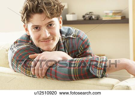 Stock Image - Man Relaxing On Sofa At Home. Fotosearch