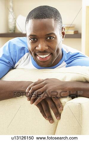 Stock Image - Man Relaxing On Sofa At Home. Fotosearch