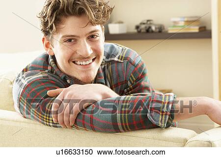 Stock Image - Man Relaxing On Sofa At Home. Fotosearch