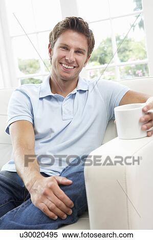 Man Sitting On Sofa Drinking Coffee Relaxing At Home View Large Photo Image Stock Photography - Man Sitting On Sofa Drinking Coffee Relaxing At Home. Fotosearch