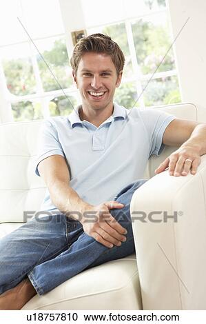 Stock Image - Man Sitting On Sofa Relaxing At Home. Fotosearch