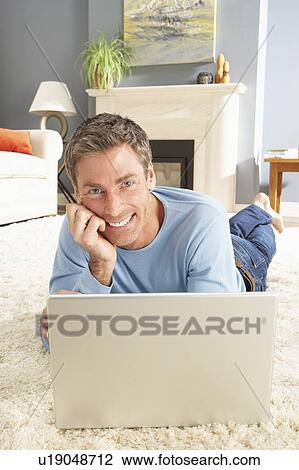 Man Using Laptop Relaxing Laying On Rug At Home View Large Photo Image Stock Image - Man Using Laptop Relaxing Laying On Rug At Home . Fotosearch