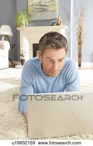 Man Using Laptop Relaxing Laying On Rug At Home View Large Photo Image Stock Photo - Man Using Laptop Relaxing Laying On Rug At Home . Fotosearch