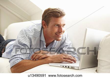 Man Using Laptop Relaxing Sitting On Sofa At Home View Large Photo Image Stock Image - Man Using Laptop Relaxing Sitting On Sofa At Home. Fotosearch