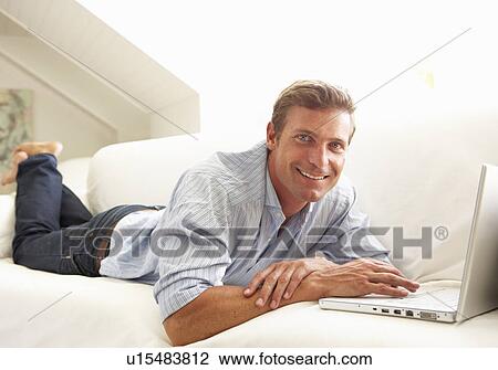 Man Using Laptop Relaxing Sitting On Sofa At Home View Large Photo Image Stock Image - Man Using Laptop Relaxing Sitting On Sofa At Home. Fotosearch