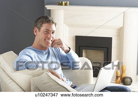 Man Using Laptop Relaxing Sitting On Sofa At Home View Large Photo Image Stock Photo - Man Using Laptop Relaxing Sitting On Sofa At Home . Fotosearch