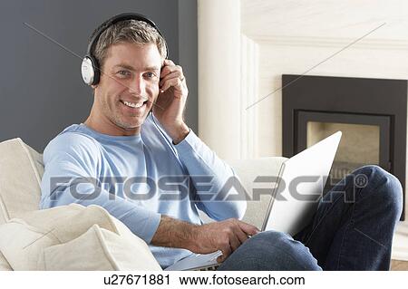 Man Using Laptop Wearing Headphones Relaxing Sitting On Sofa At Home View Large Photo Image Stock Image - Man Using Laptop Wearing Headphones Relaxing Sitting On Sofa At Home . Fotosearch