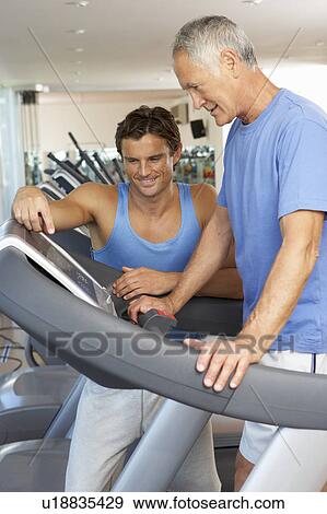 Stock Photo - Man Working With Personal Trainer On Running Machine In Gym. Fotosearch